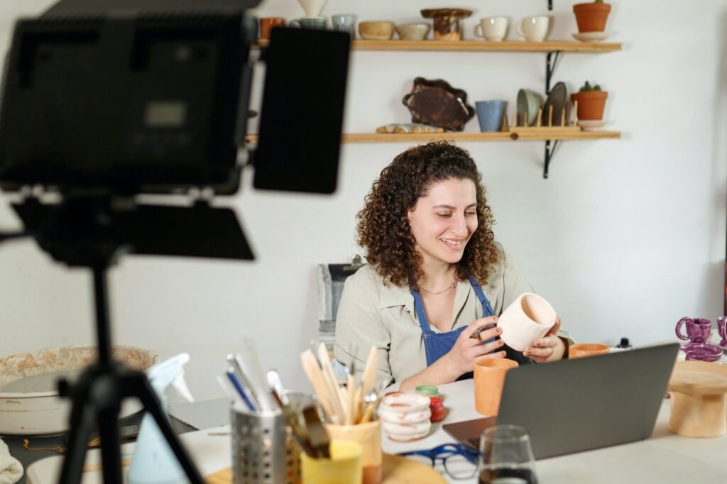 Females potter in blue apron making a vlog, recording online course, clay master class.