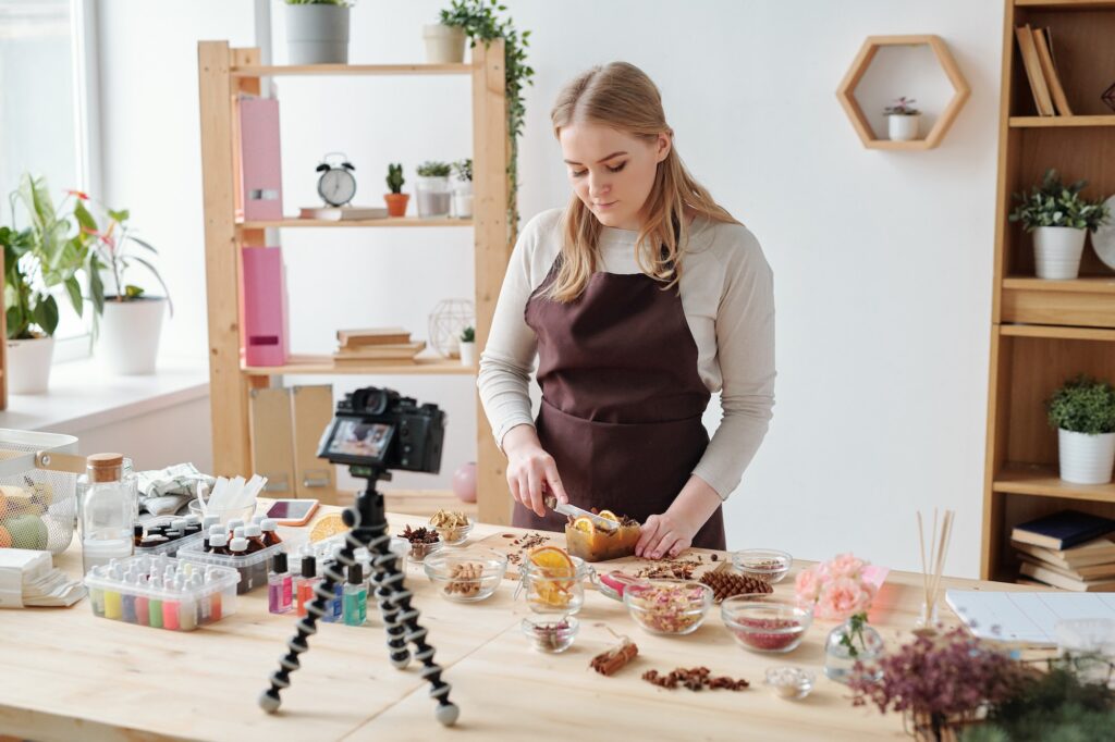 Young craftswoman shooting home master class of making handmade soap on camera
