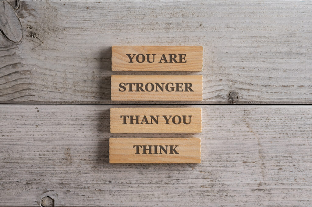 You are stronger than you think sign written over a stack of four wooden pegs